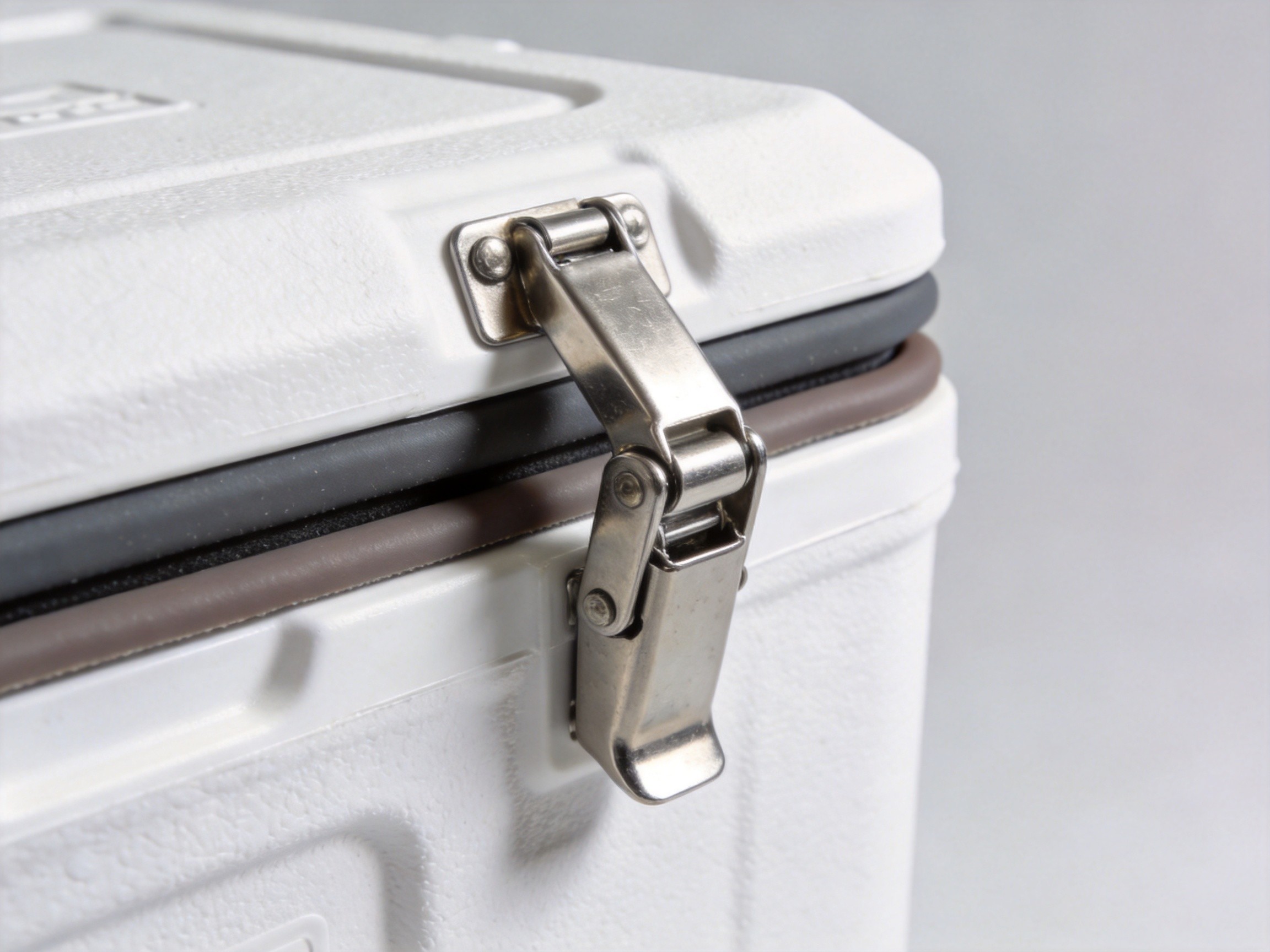 Swing arm latch mounted on an insulated cooler case, showing compressed gasket seal